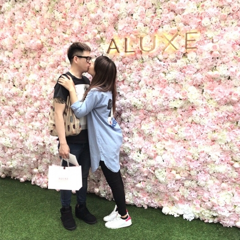 The passionate couple against a romantic flower wall, the air filled with pink bubbles.