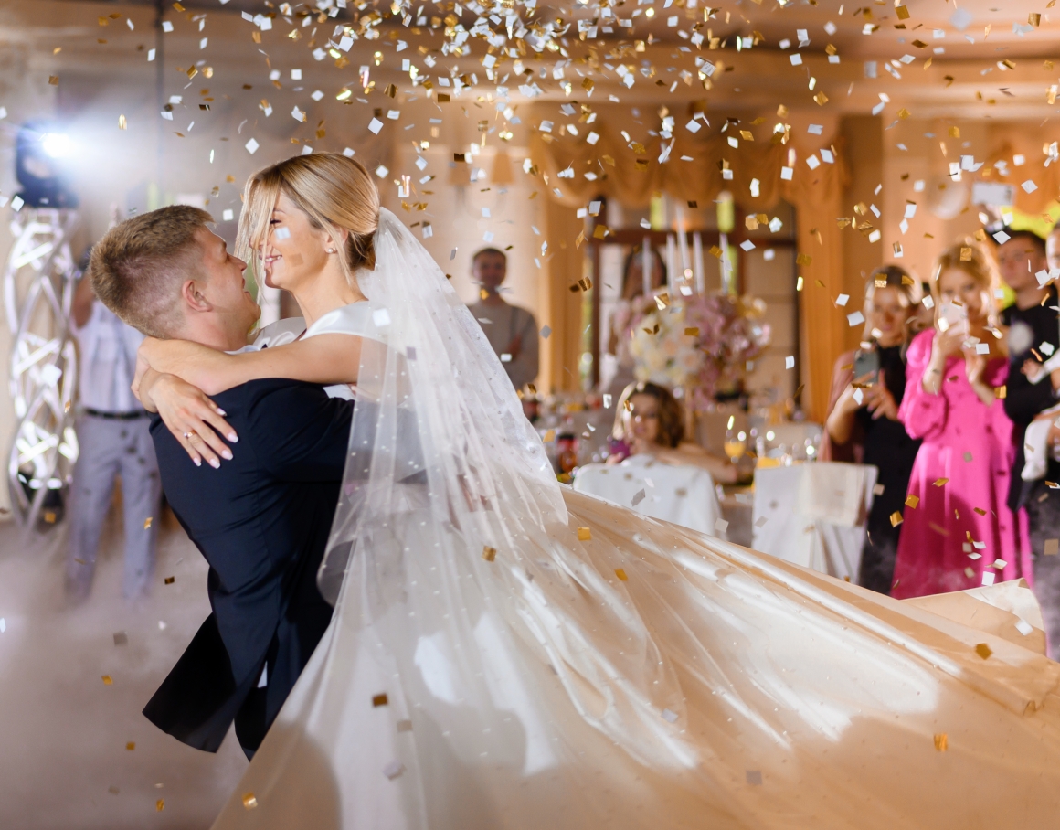 bride-couple-waving-while-dacning-with-confetti